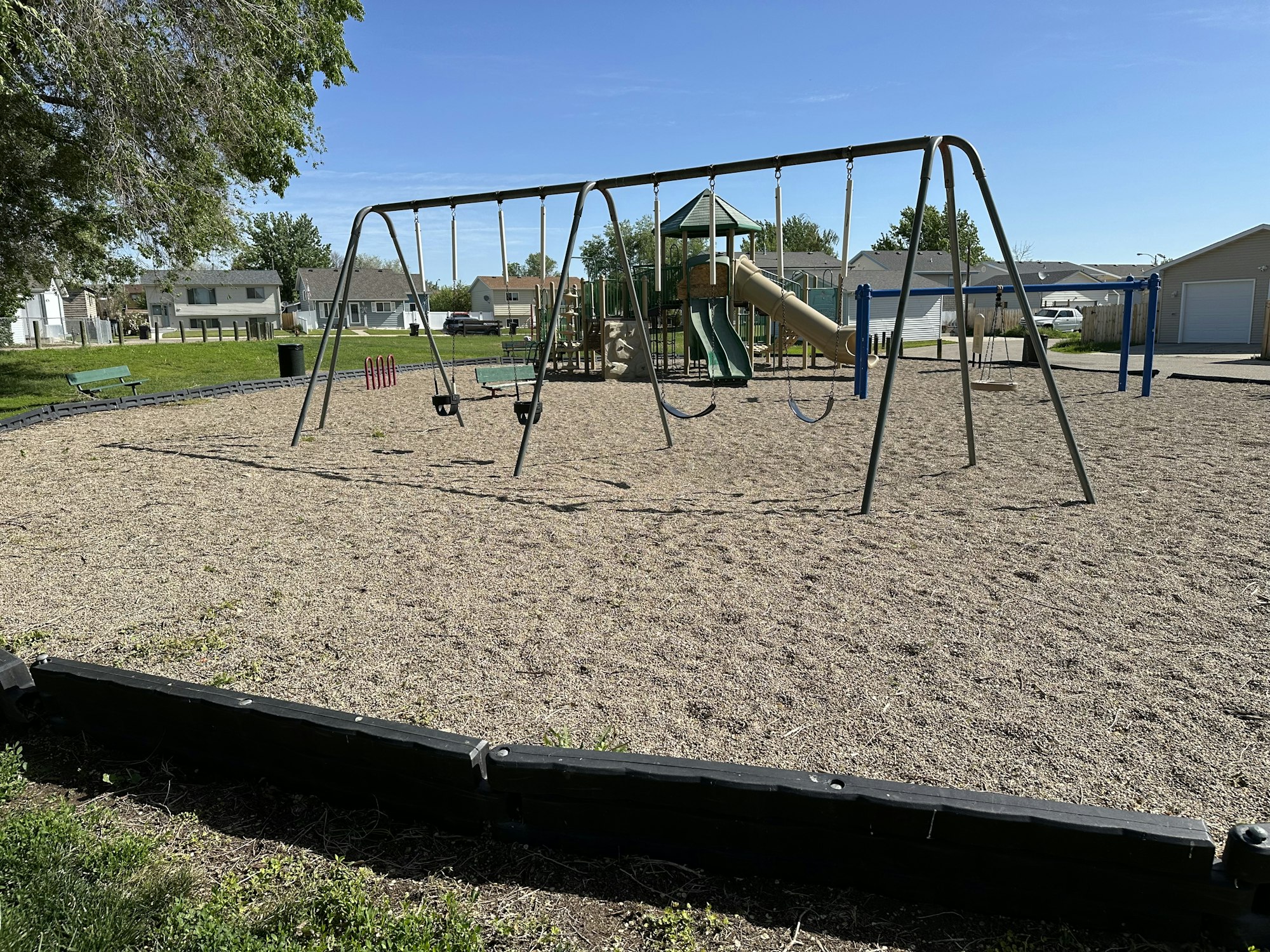 A playground with swings, a slide, and climbing structures on a sunny day.