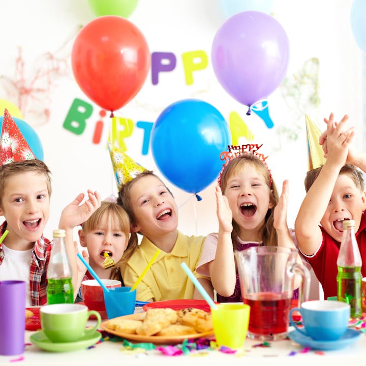 Kids celebrating a birthday party with colorful hats, balloons, and decorations.