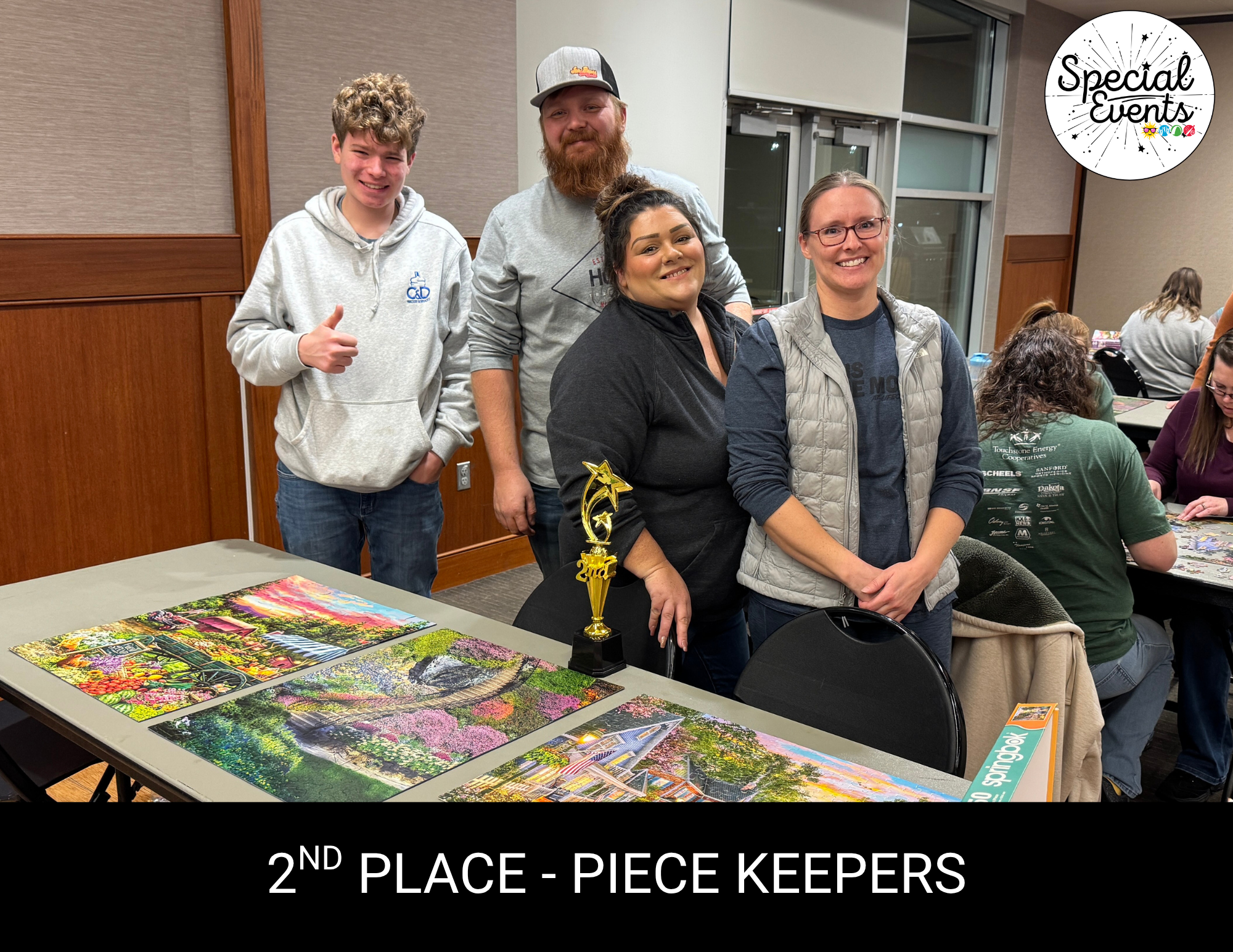 The image shows a group of four individuals posing with a trophy for their 2nd place finish in a puzzle competition.
