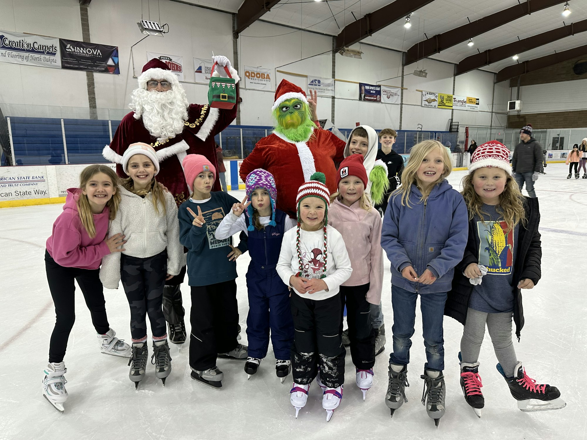 Santa Claus and the Grinch with kids on an ice skating rink.