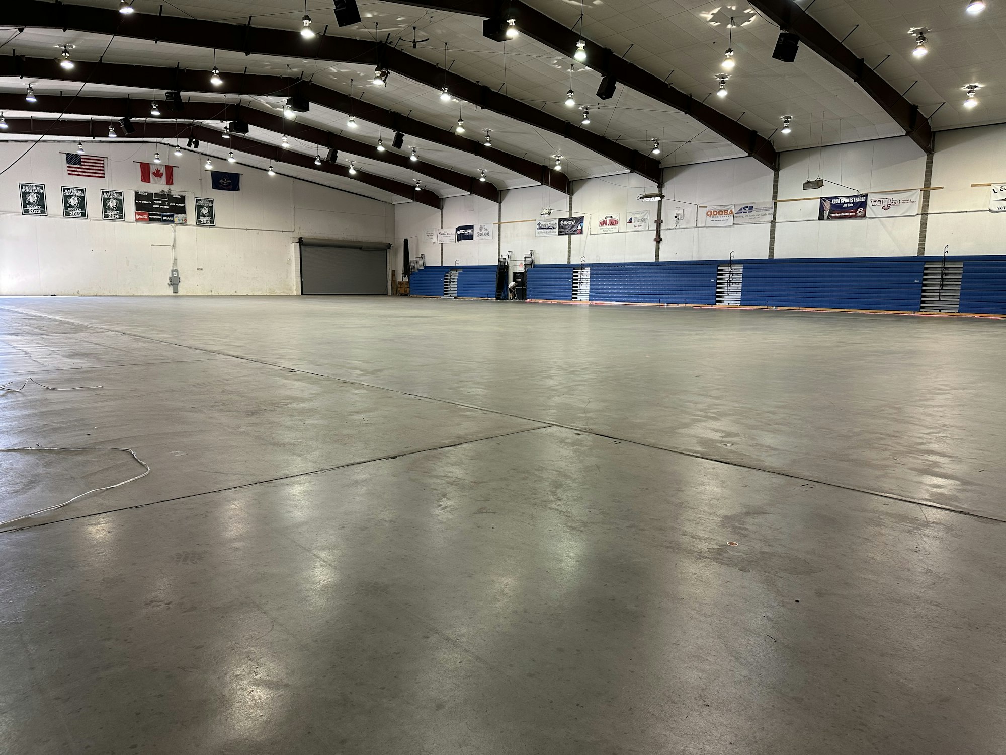 Empty indoor sports arena with bleachers, banners, and flags.