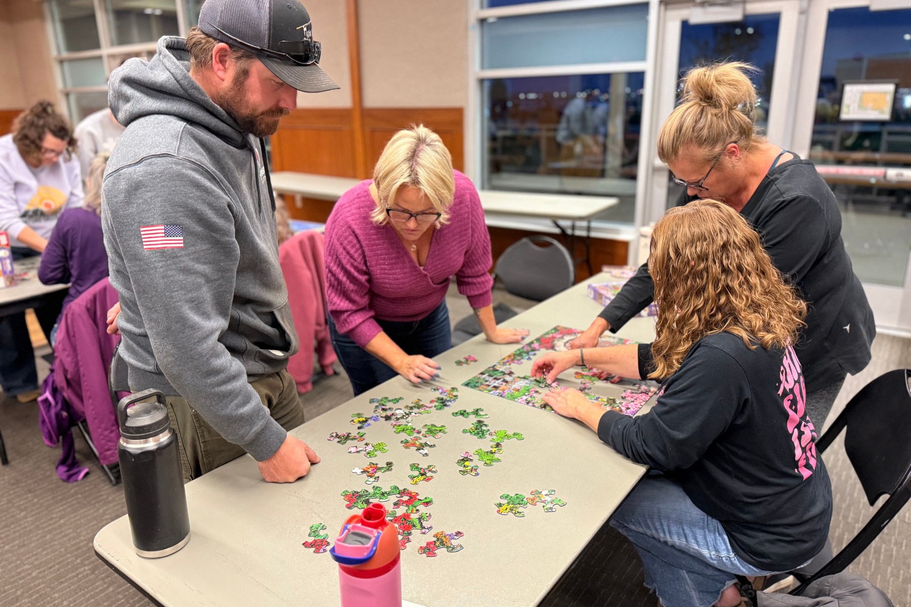 People working on a jigsaw puzzle together at a table in a community space.