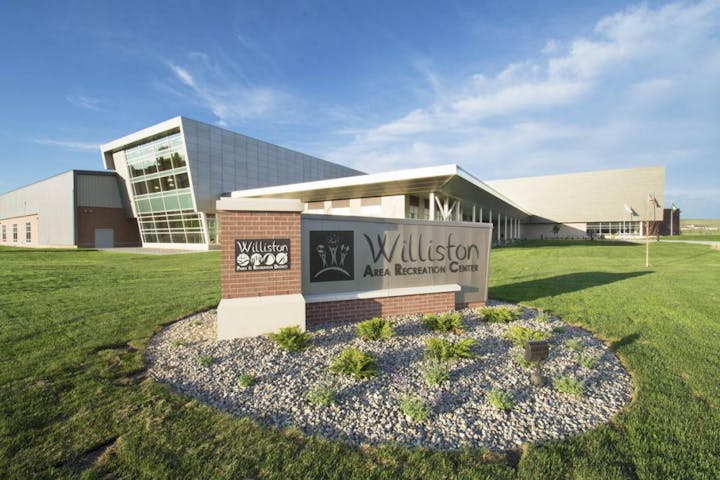 Modern recreational center building with sign in front, clear skies.