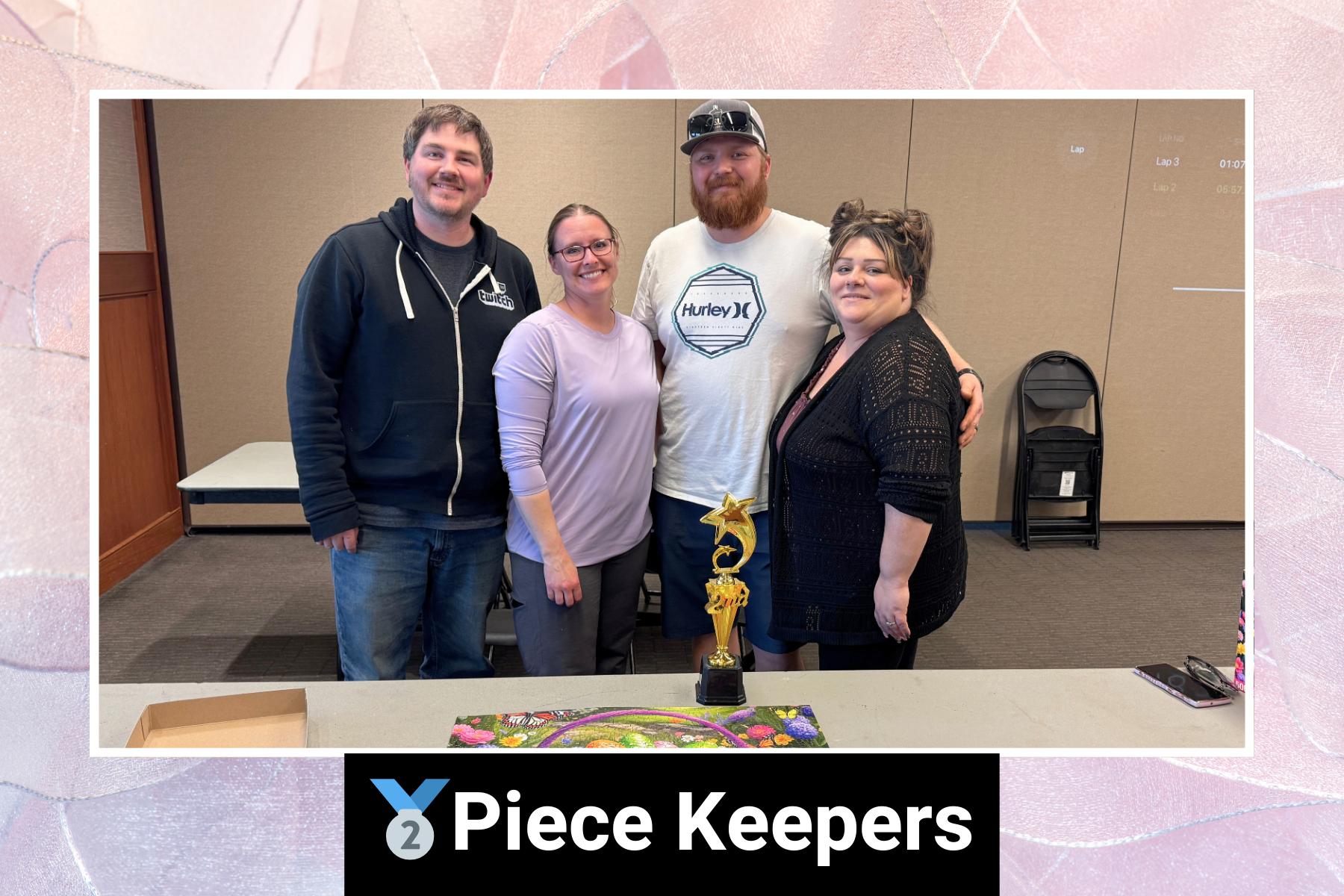 Four people standing together with a trophy on the table. Text reads "Piece Keepers."