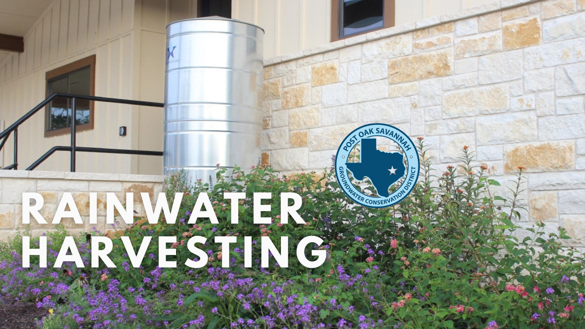 The image showcases a rainwater harvesting system outside a building, featuring a storage tank and flowering plants.