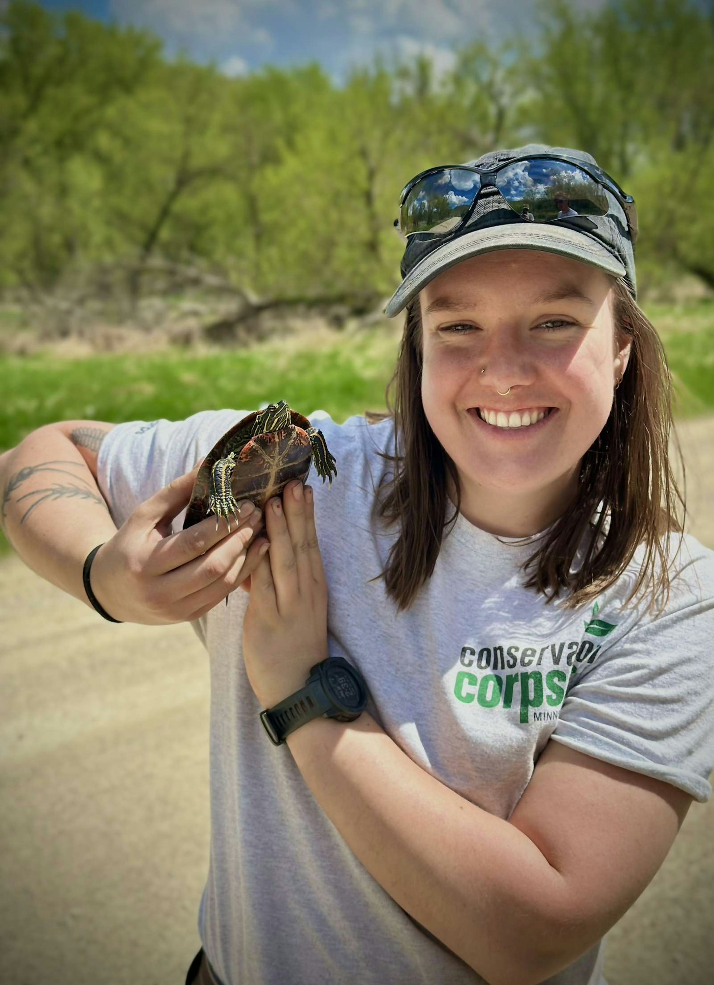 A person smiling and holding a turtle outdoors.