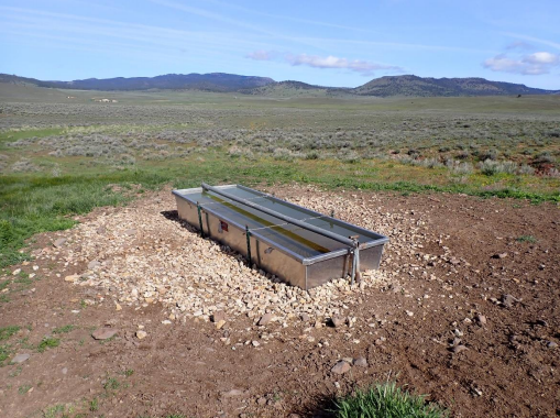 A small structure with solar panels in an open field.