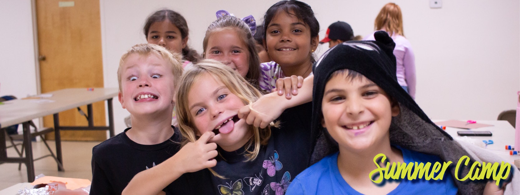 Group of kids making funny faces at summer camp indoors.