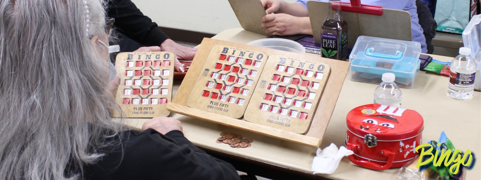 People playing bingo with boards, snacks, and drinks on the table.