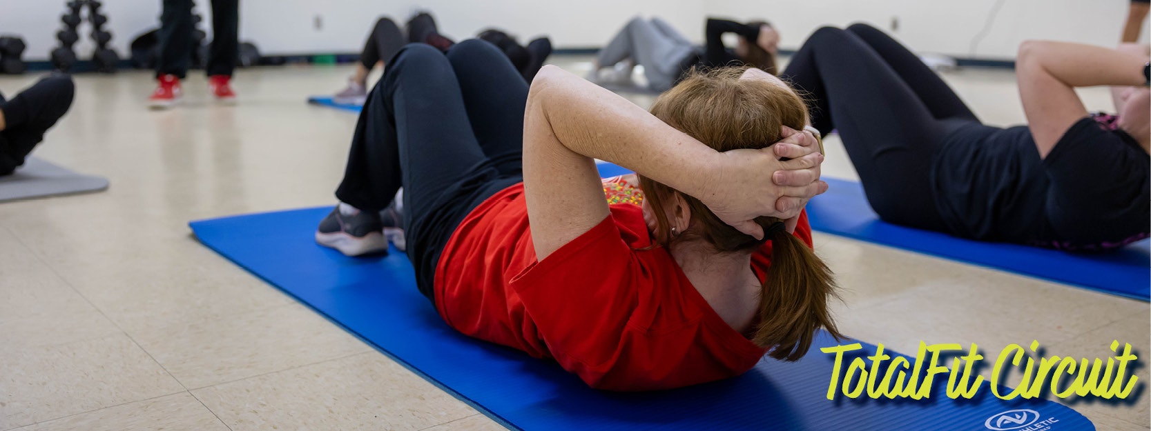 People exercising on mats in a fitness class, with "TotalFit Circuit" text in the corner.