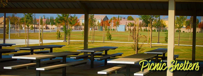 An outdoor picnic shelter with tables, surrounded by greenery and open space, perfect for gatherings.
