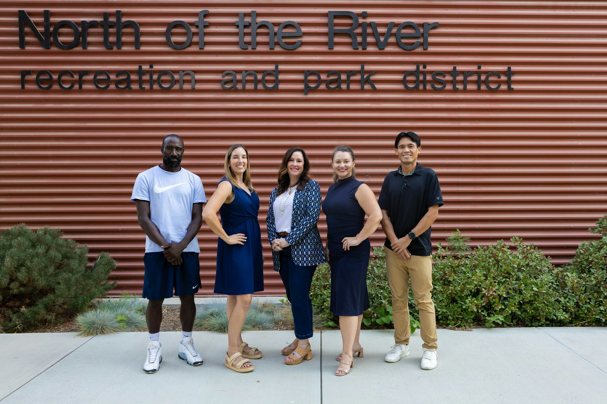 Five people stand in front of a building labeled "North of the River recreation and park district."