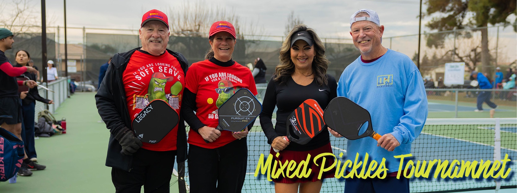Four people smiling with pickleball paddles at "Mixed Pickles Tournament".