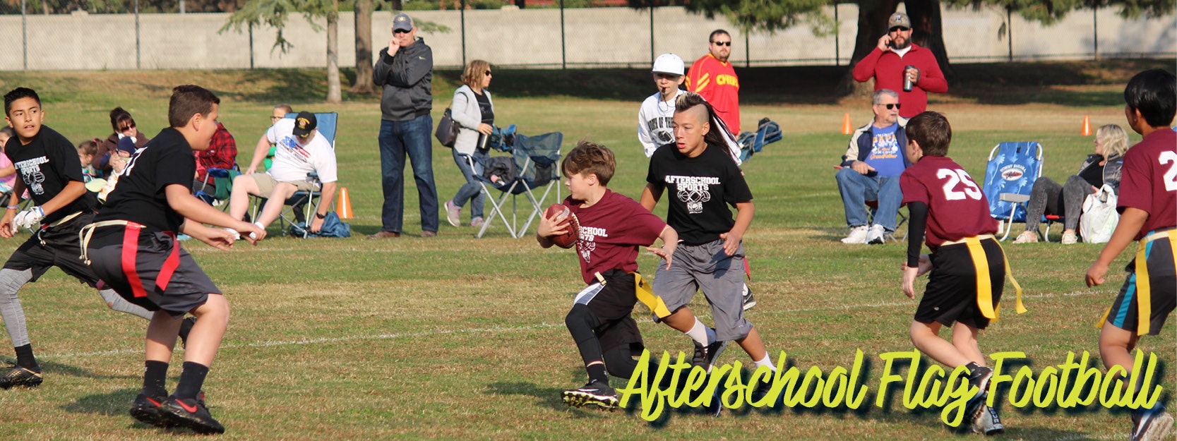 Kids playing afterschool flag football with spectators watching.