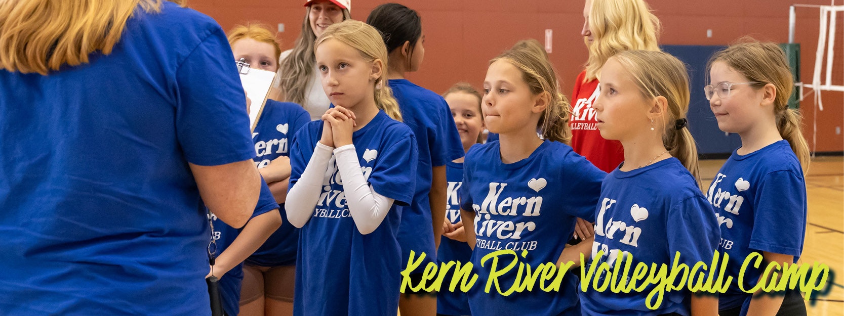Young girls in blue "Kern River Volleyball Club" shirts at a volleyball camp.