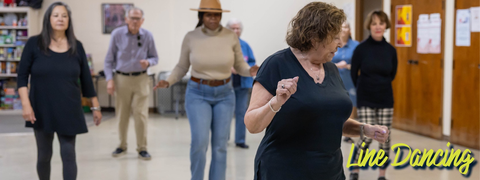 Adults line dancing in a room, following coordinated steps. Text: "Line Dancing".