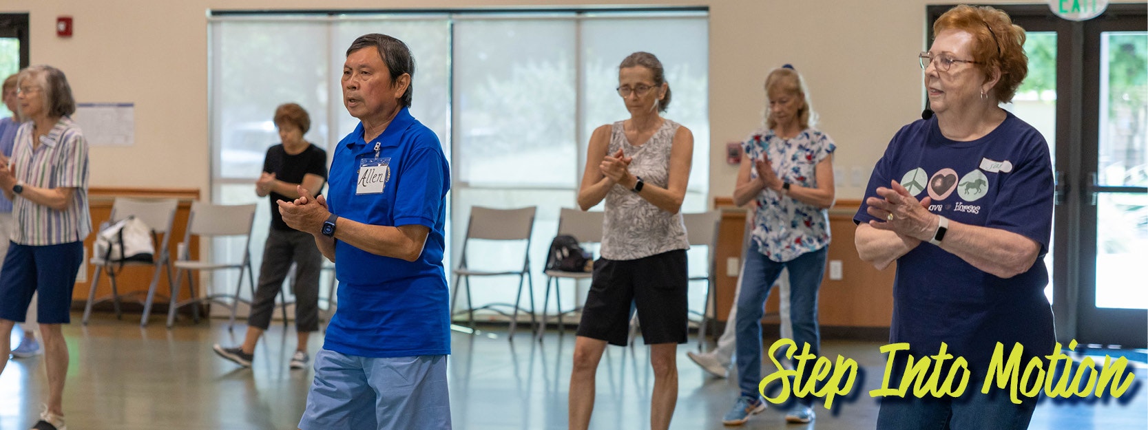 A group of people participating in a fitness or dance class indoors, with "Step Into Motion" text overlayed.