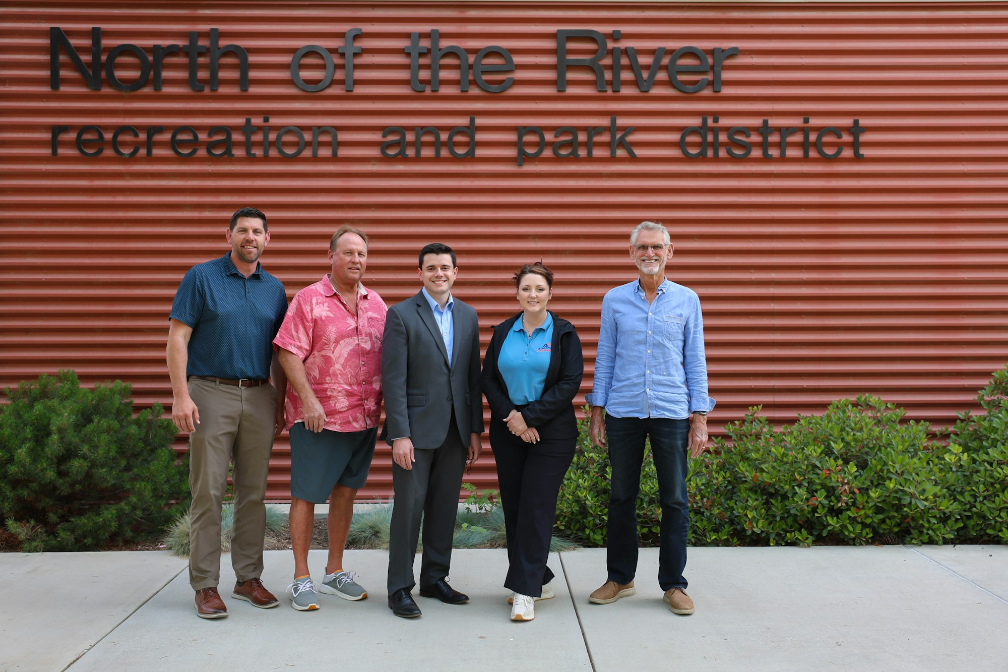 Five individuals stand in front of a building with the sign "North of the River recreation and park district."