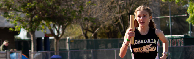 A runner in a "Rosedale Track & Field" uniform holding a baton during a relay race.