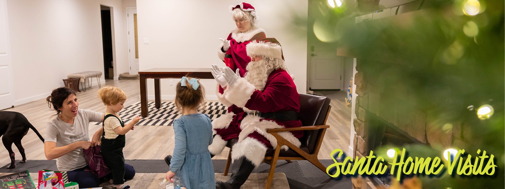 Family enjoying a visit from Santa and Mrs. Claus at home, with kids and a dog nearby.