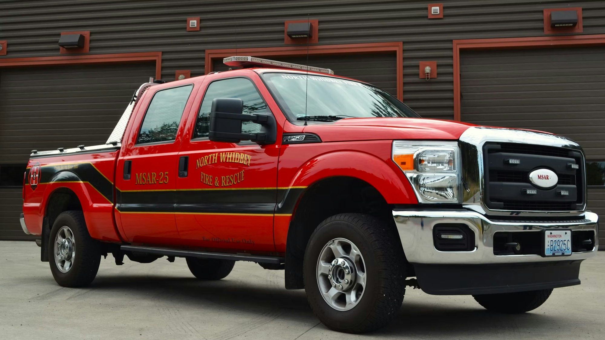 Red fire and rescue truck labeled "North Whidbey Fire & Rescue," parked in front of a garage.