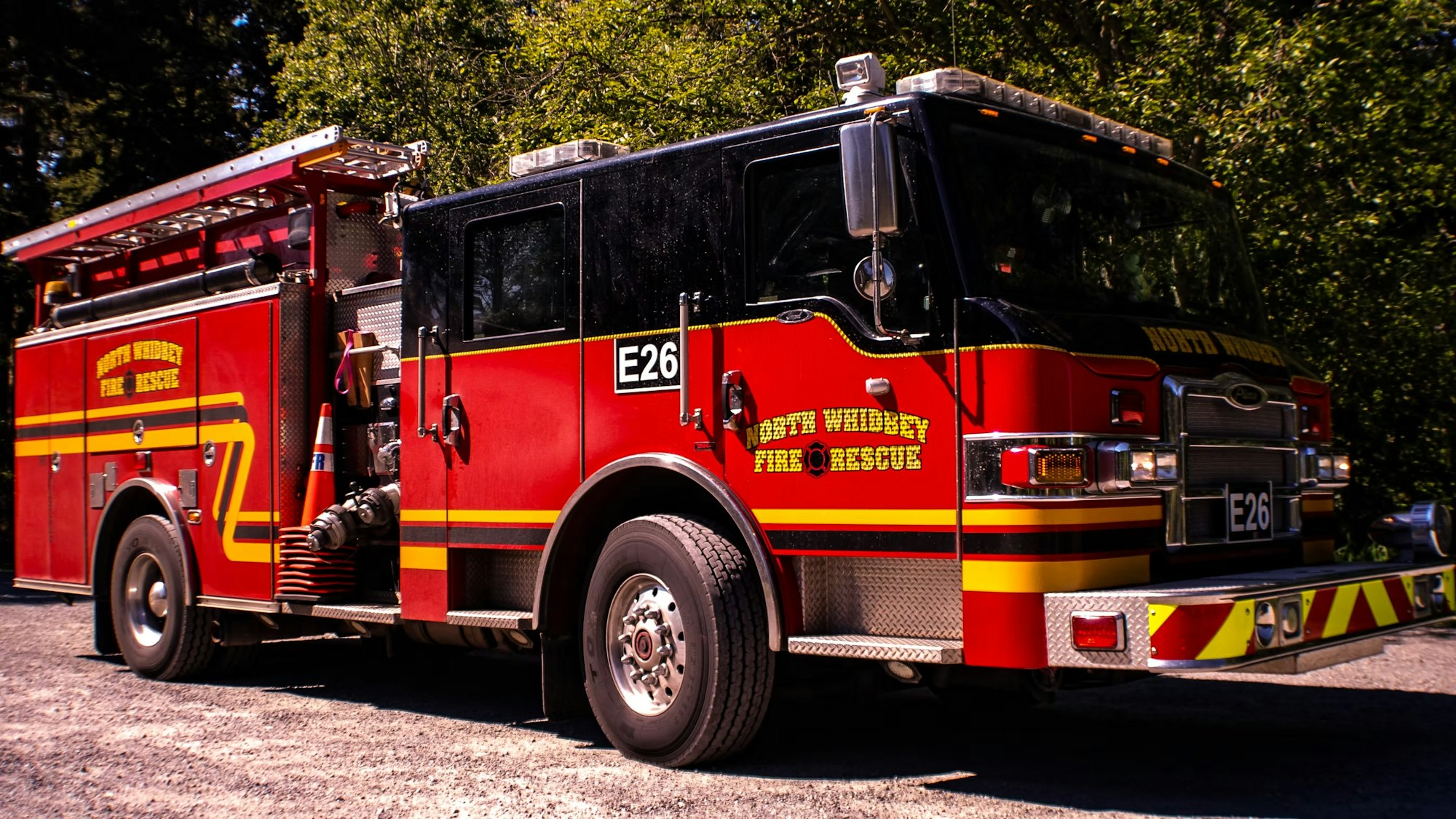 A red and black fire truck from North Whidbey Fire and Rescue parked outdoors in sunlight.