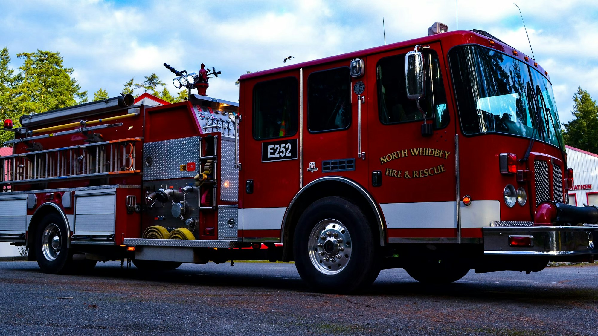 Red fire truck labeled "North Whidbey Fire & Rescue" with equipment and hoses on a paved area.