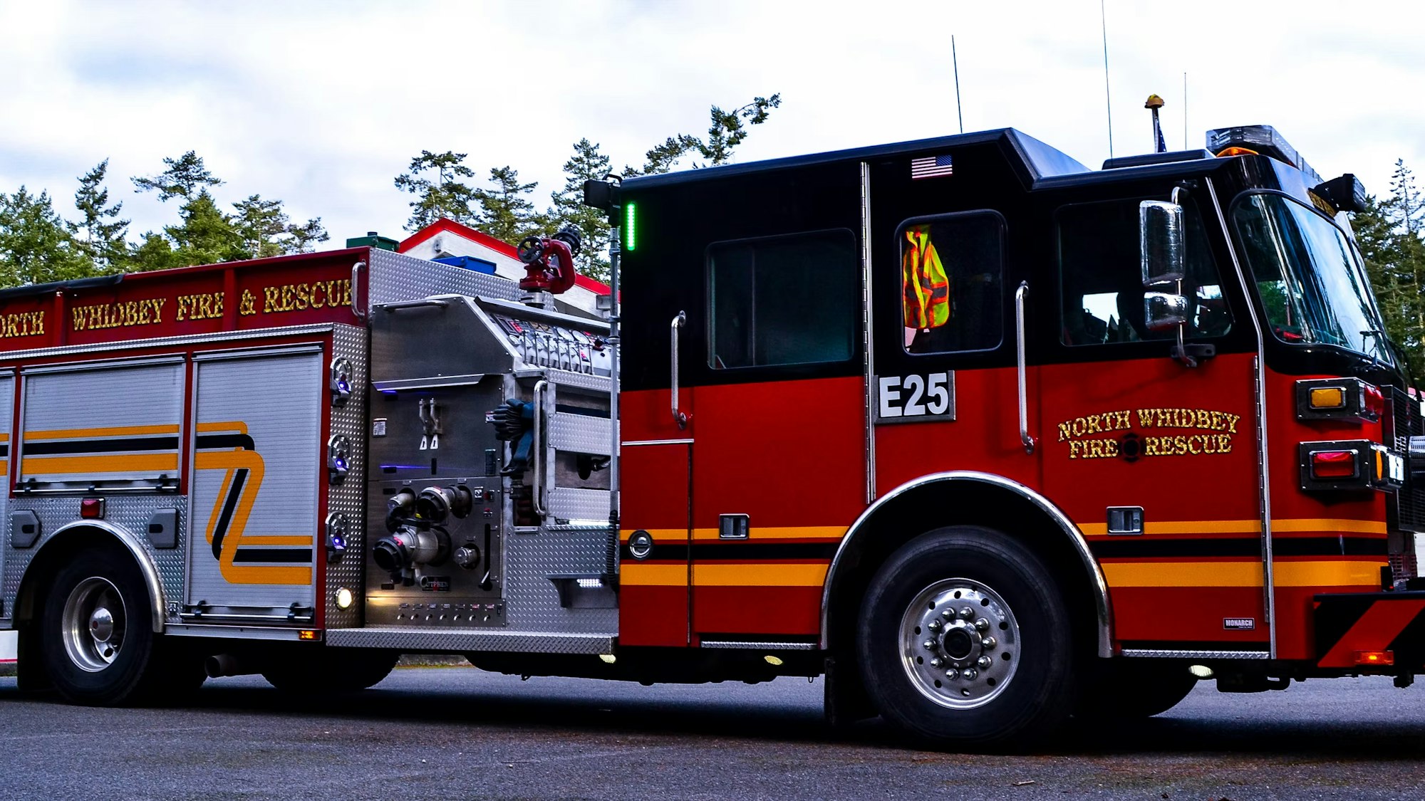 Red fire truck labeled "North Whidbey Fire & Rescue," parked with trees in the background.
