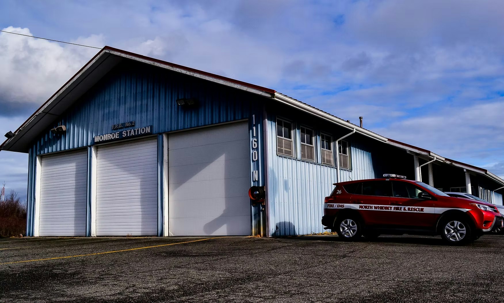 A fire station labeled "Monroe Station" with a red North Whidbey Fire & Rescue vehicle parked outside.