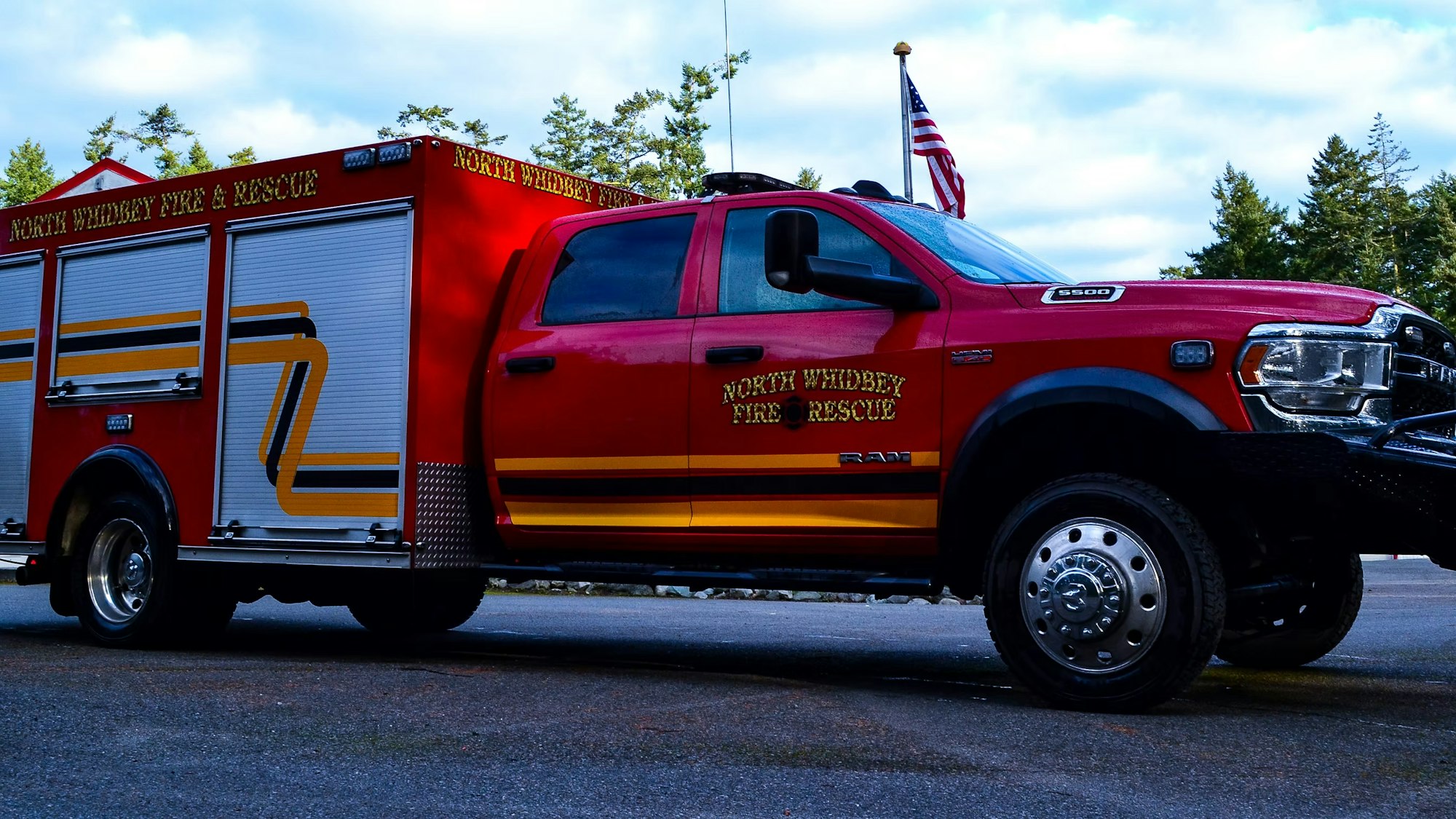 Red fire rescue truck labeled "North Whidbey Fire & Rescue" with an American flag in the background.