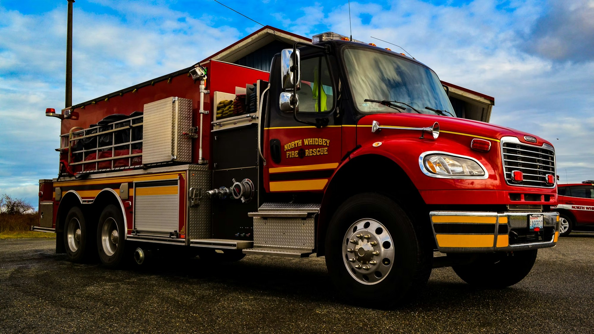 A red fire truck labeled "North Whidbey Fire Rescue" parked outdoors under a blue sky.