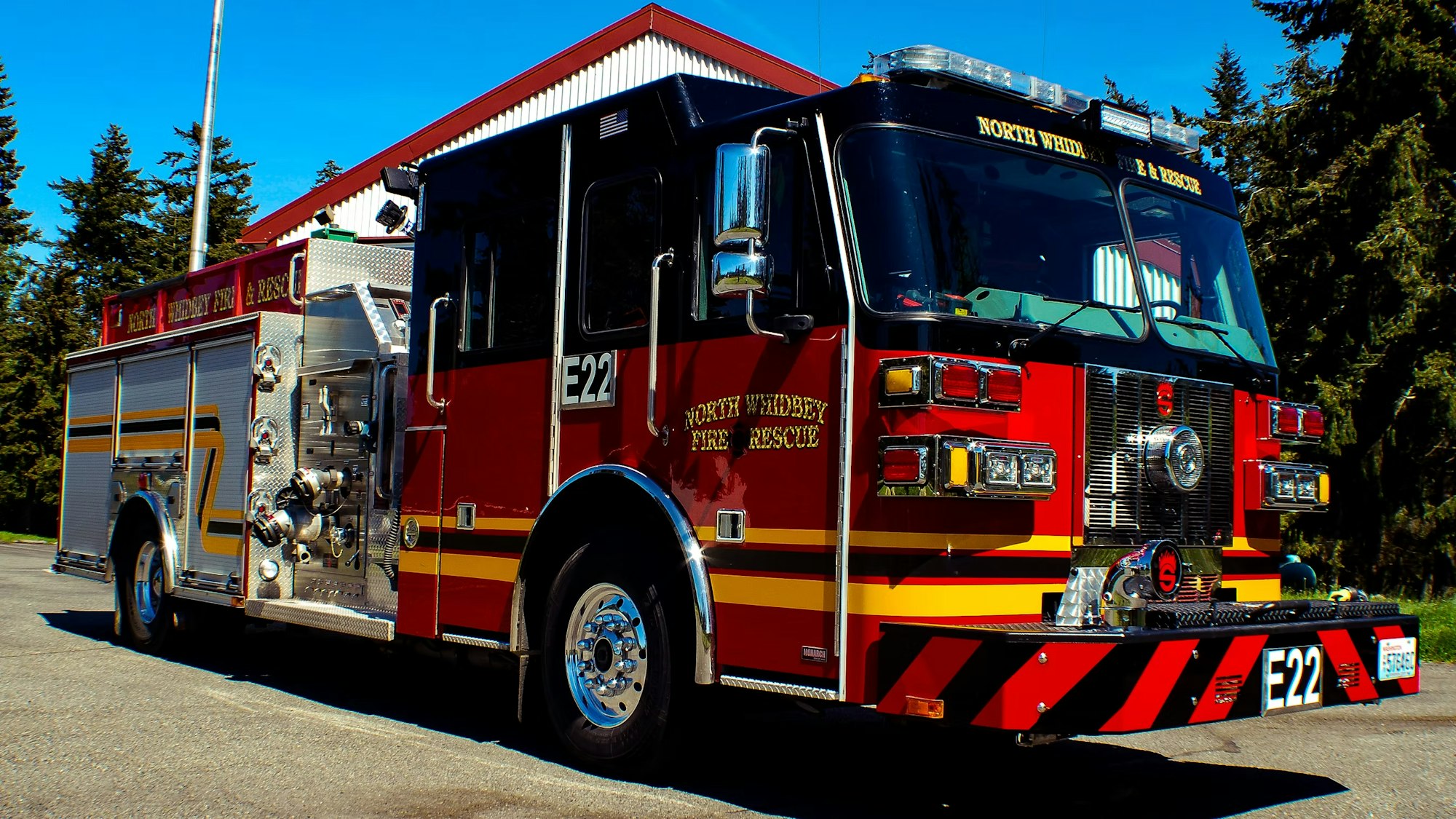 A red and yellow fire truck parked in front of a building, labeled "North Whidbey Fire & Rescue."