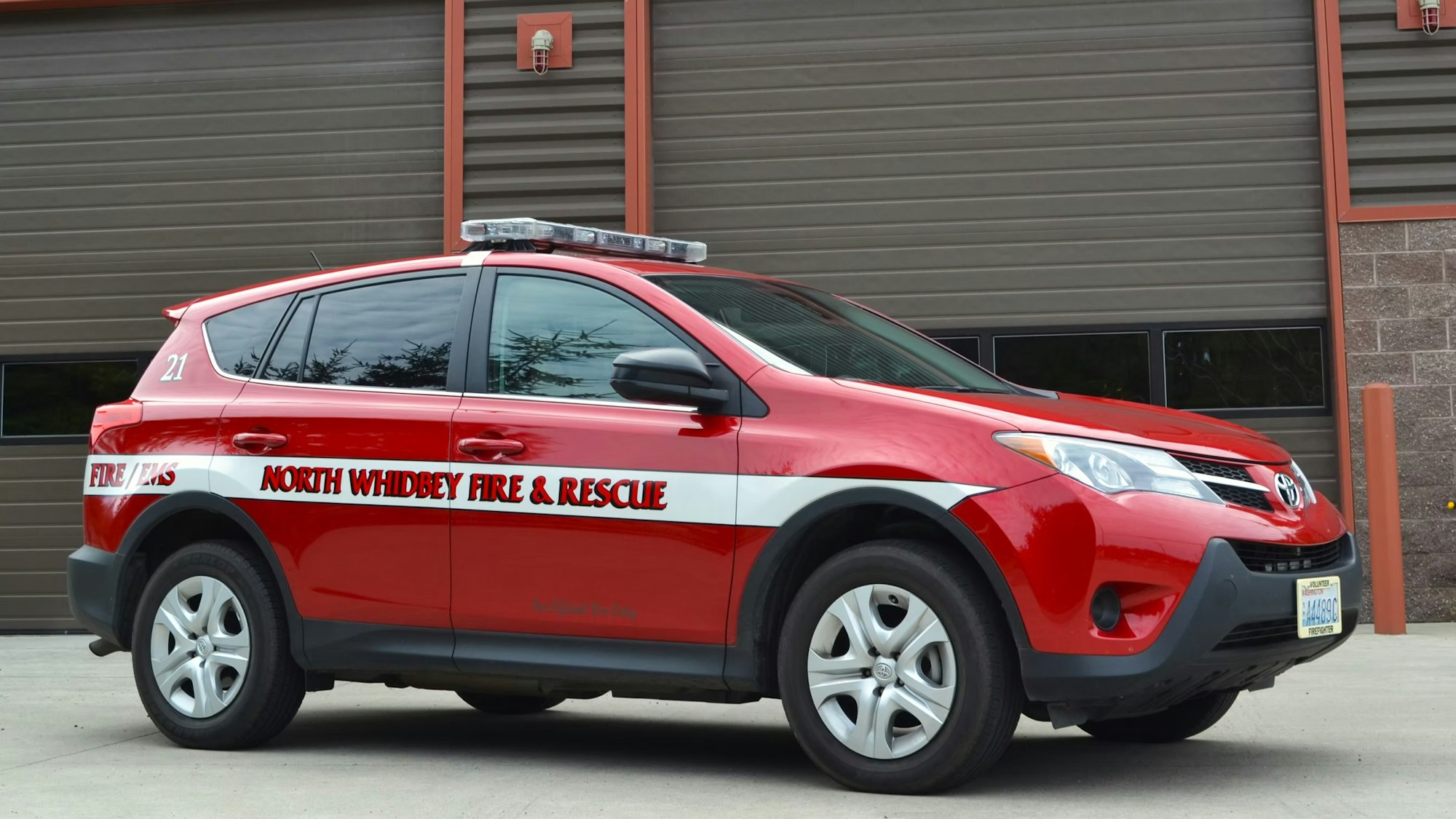 Red Toyota vehicle labeled "North Whidbey Fire & Rescue" parked in front of a building.