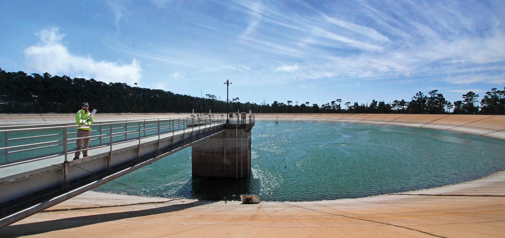 A water treatment facility with a person in high-visibility clothing inspecting the site.