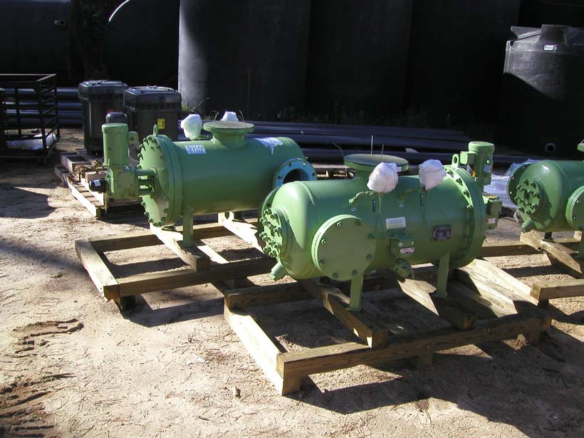 Green industrial pumps on wooden pallets, outdoor setting, possibly a storage or staging area for equipment.