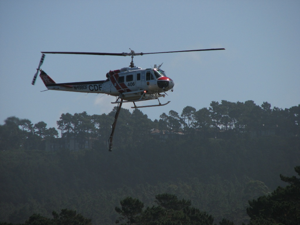 A helicopter flying against a backdrop of trees.