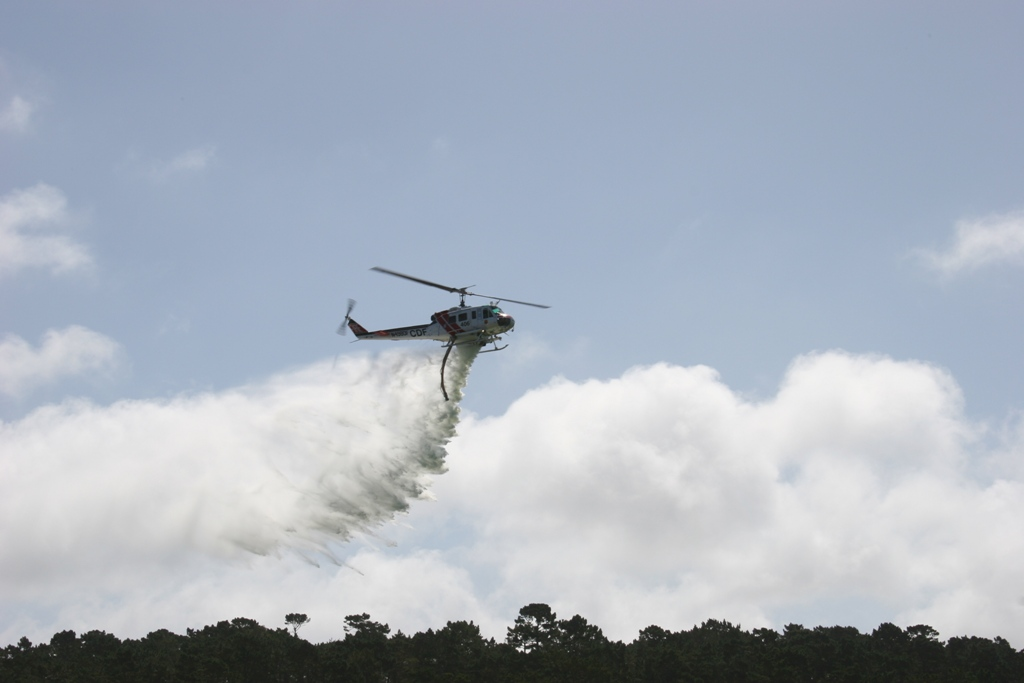 Helicopter releasing water in sky, possibly for firefighting.