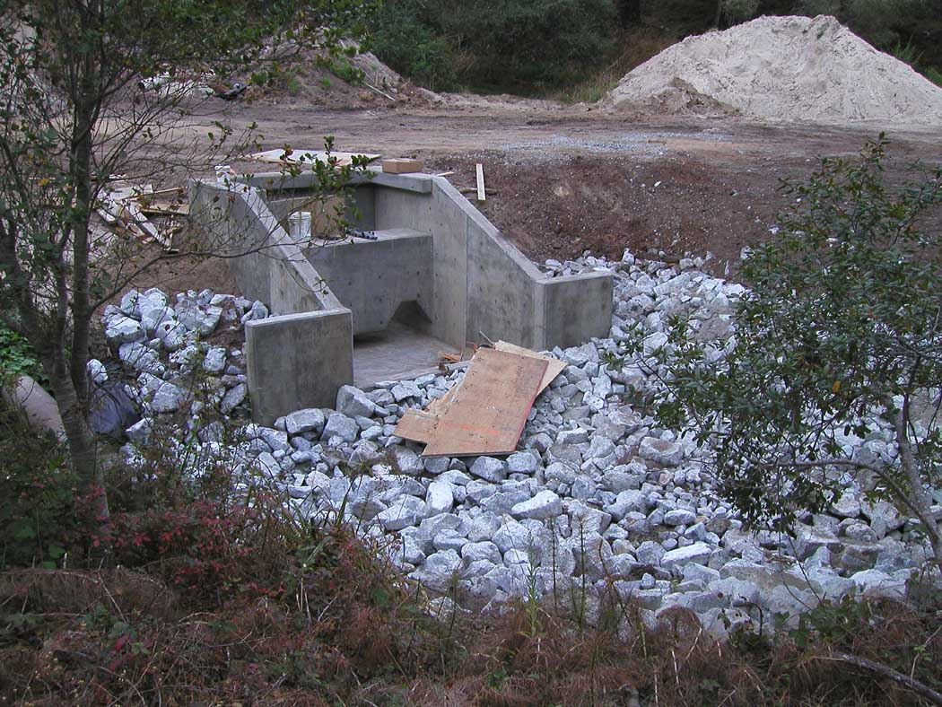 A construction site with concrete foundations and piled rocks.