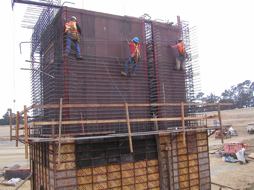 Construction workers on rebar framework at a building site.
