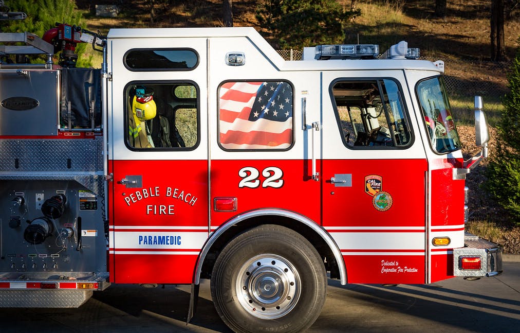 A red and white fire truck labeled "Pebble Beach Fire," with an American flag on the window and "22" on the side.