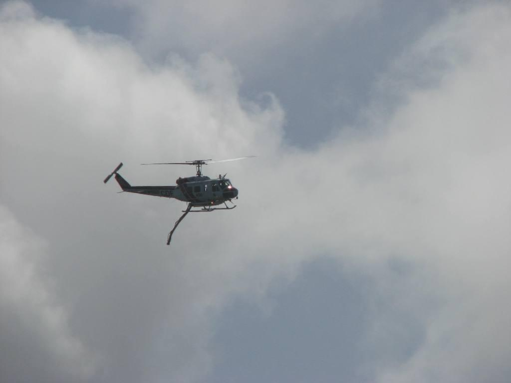 A helicopter flying against a cloudy sky.