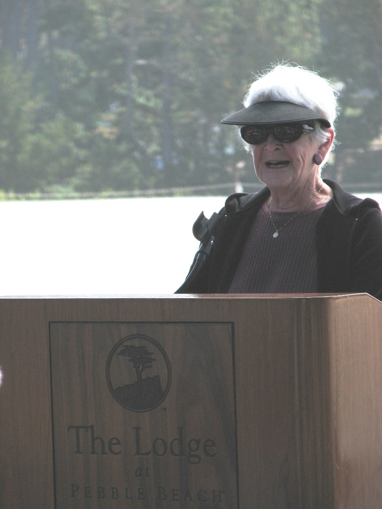 Person speaking at a podium labeled "The Lodge at Pebble Beach."
