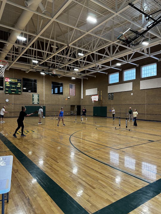 People playing pickleball in a gymnasium.