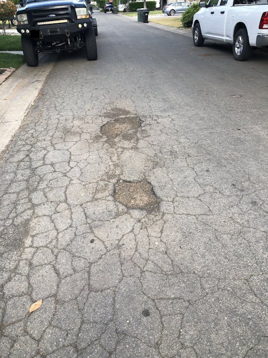 photo of two potholes and crumbling asphalt pavement
