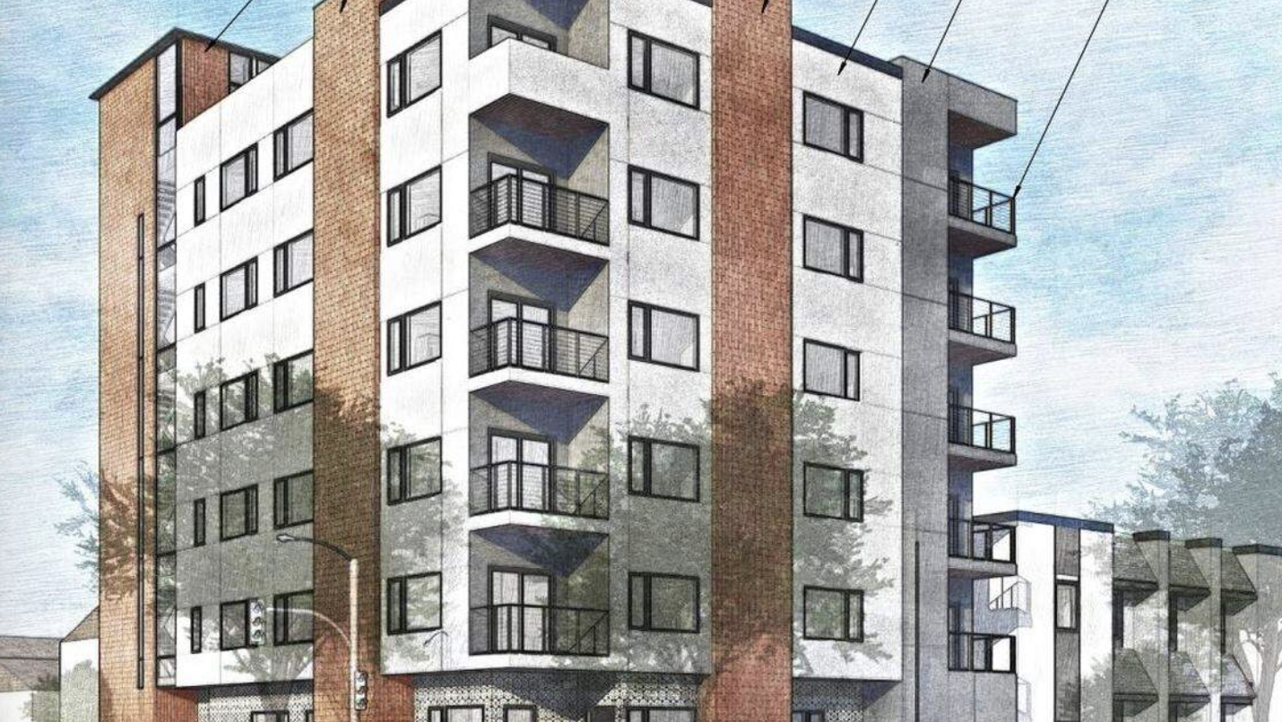 A six-story building with balconies, featuring a mix of brick and white exterior panels.