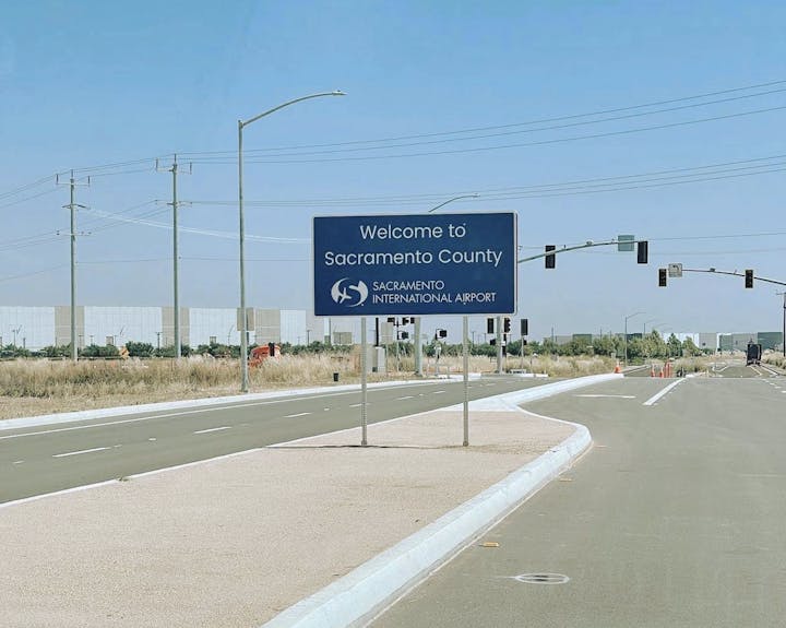 Welcome sign to Sacramento County and Sacramento International Airport by a road.