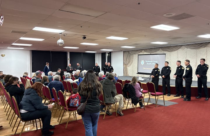 A community meeting featuring Sacramento County Sheriff's Office officers speaking to an audience in a large hall.