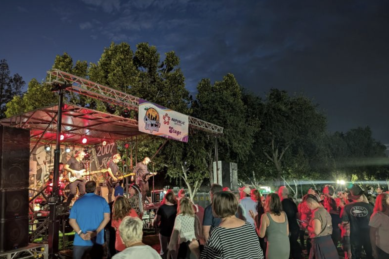 A lively outdoor concert scene at night, with a band performing and an engaged crowd enjoying the music under the stars.