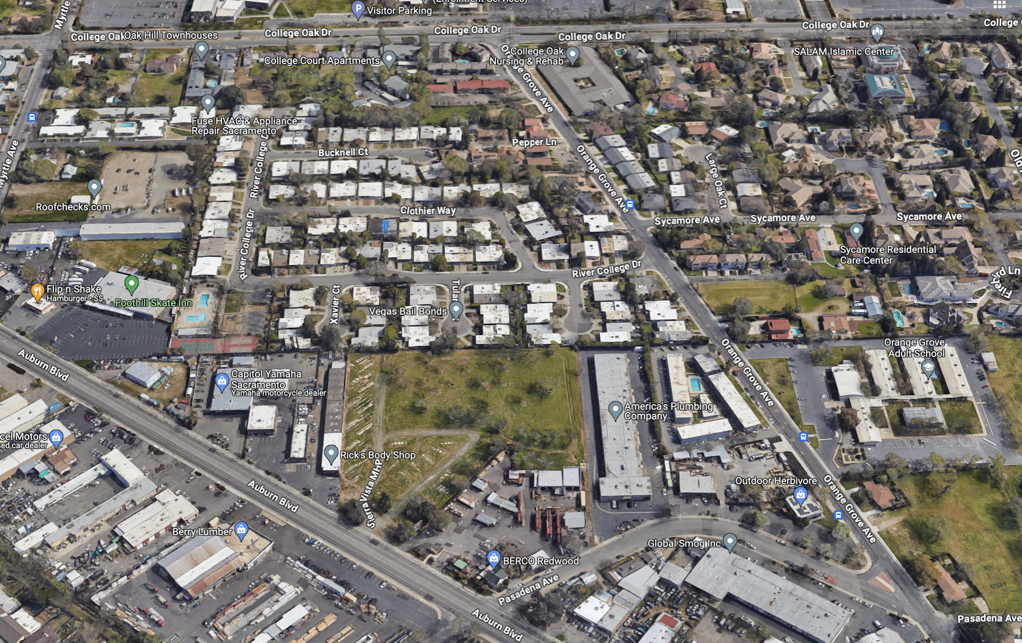 An aerial view of an urban area with roads, buildings, parking lots, and labeled businesses.