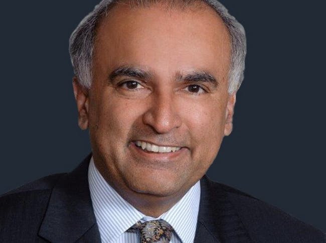 The image features a professional-looking man with a friendly smile, wearing a suit and tie against a dark background.